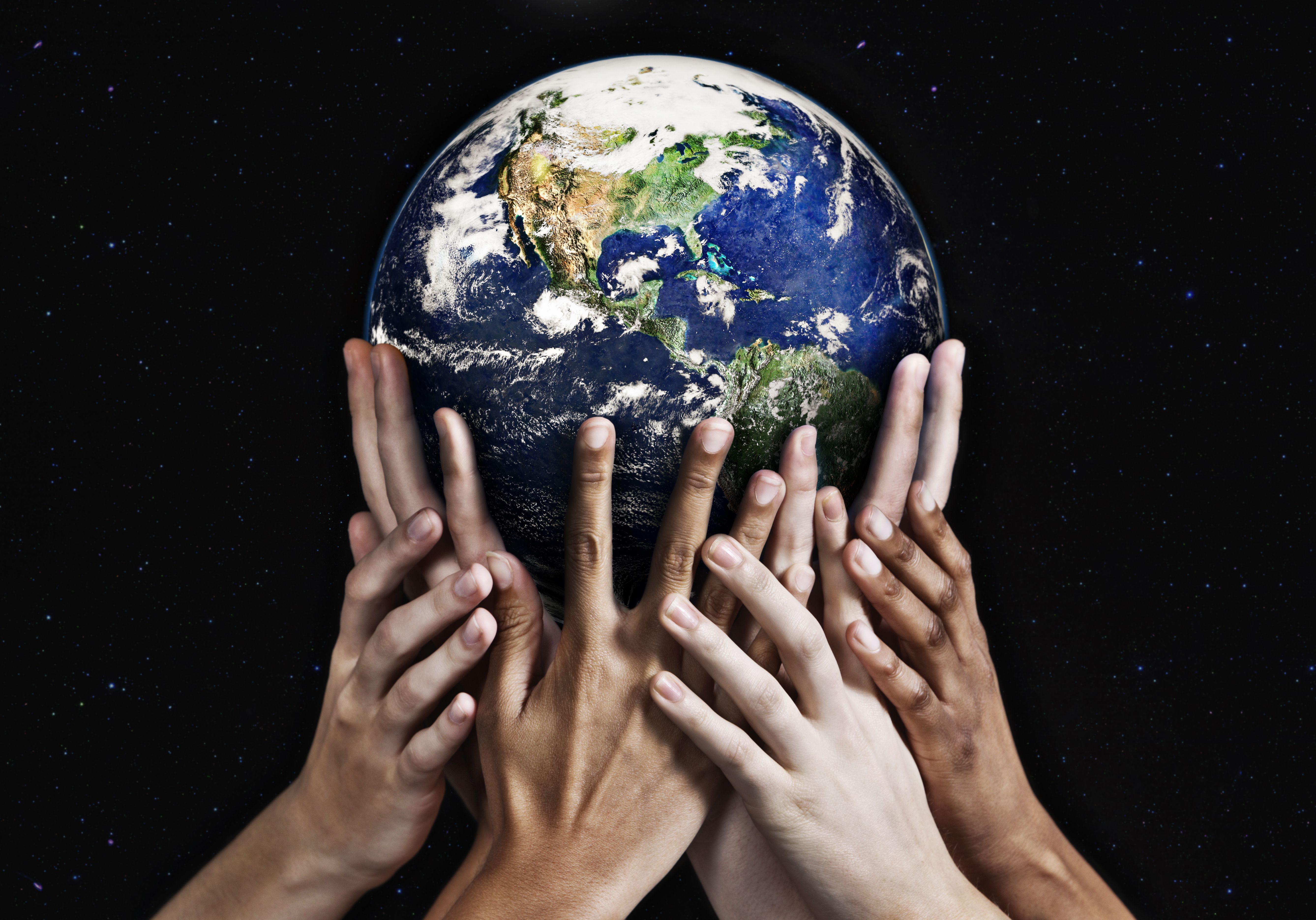image of globe being held up by diverse group of hands