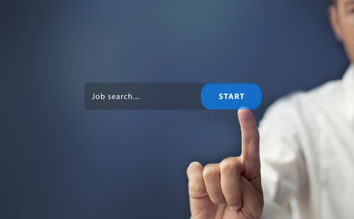 A job applicant clicking on an online job search bar.
