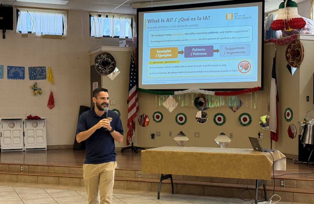 Luis A. Garnica Chavira speaks with a microphone in front of a projected bilingual slide titled What Is AI? and ¿Qué es la IA? at the San Juan Senior Center.