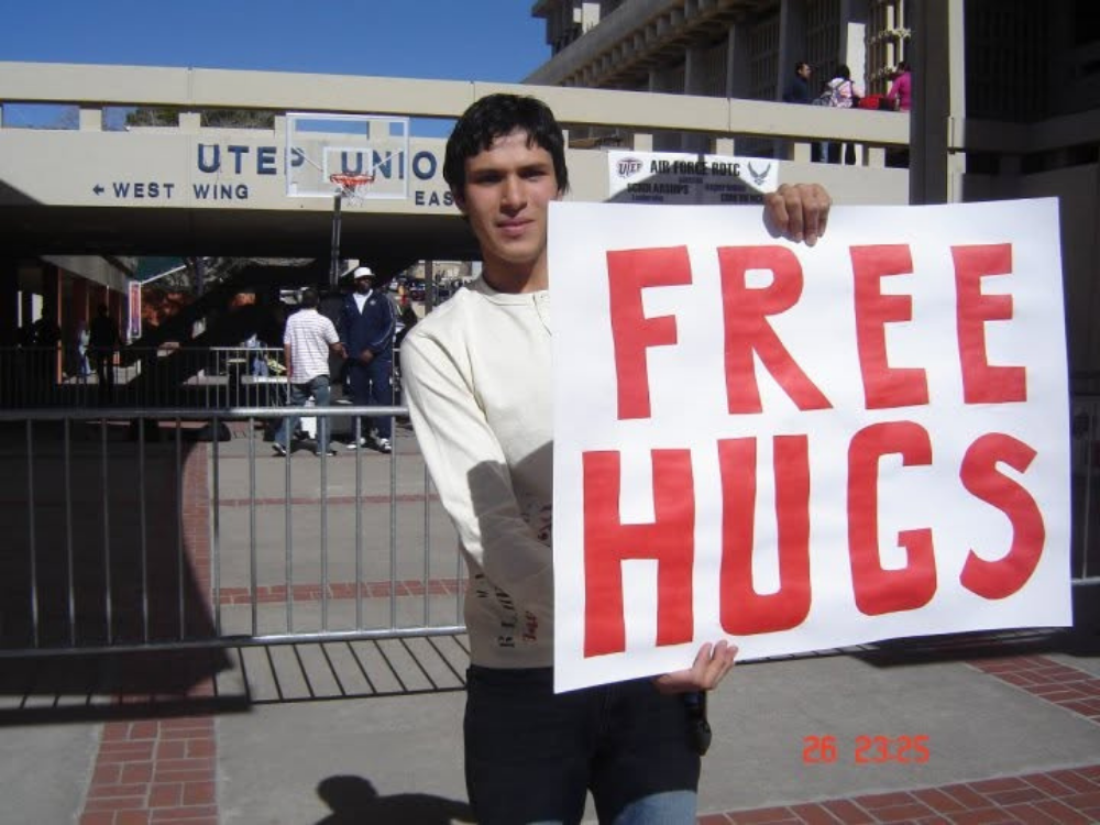 Alejandro Muñoz holding a Free Hugs sign during his student years at UTEP
