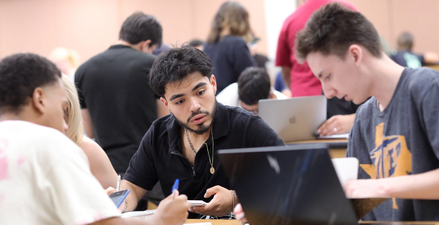 Hunt College students collaborating around a laptop in class.