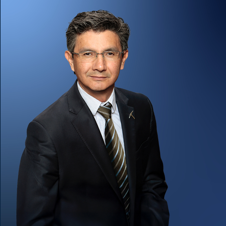 Professional portrait of César Carrasco smiling while seated in an office setting.