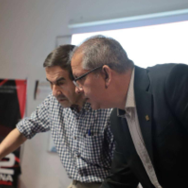 Two individuals collaborate in a research environment as text highlights a partnership between Loya Engineering and UACJ to advance binational AI research. 