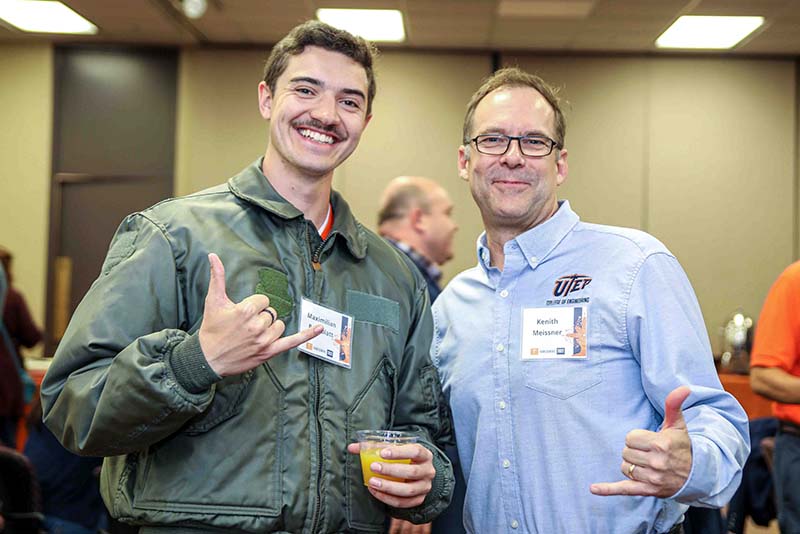 Maximilian Rothblatt and Kenith Meissner posing together at an indoor networking event while making hand gestures toward the camera.