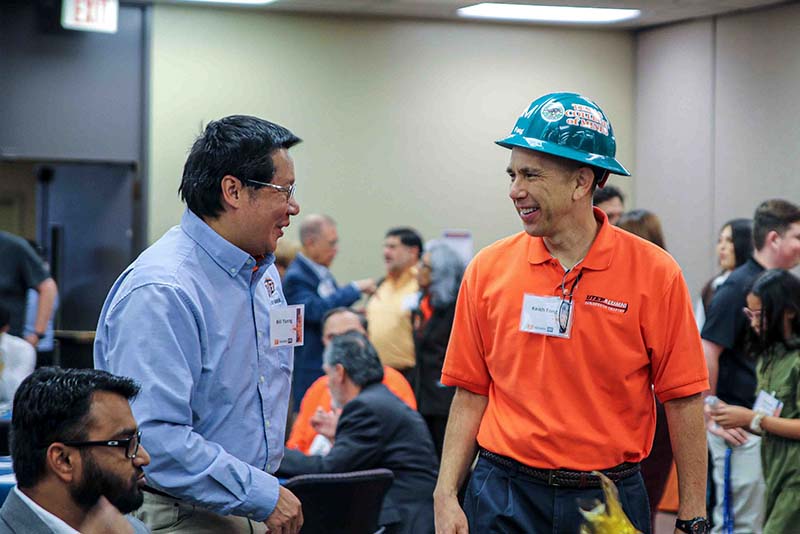 Bill Tseng and Keith Fong standing and talking during an indoor networking event.