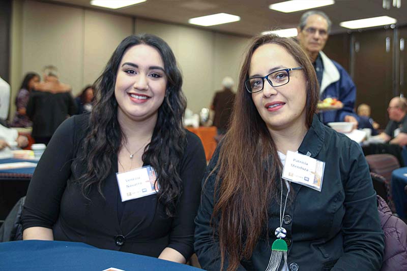 Venezia Navarro seated at a table posing with Patricia Mendoza during the Loya Engineering 2022 Homecoming breakfast.