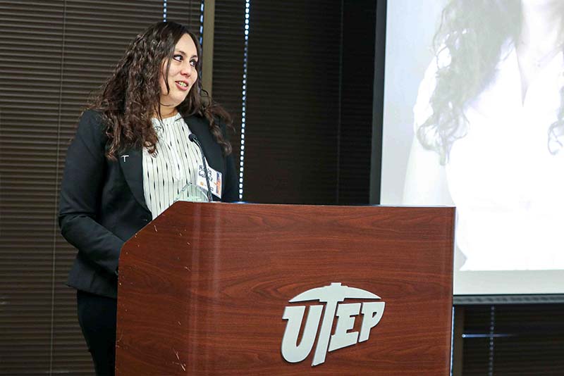 Maria speaking at a podium beside a projection screen.