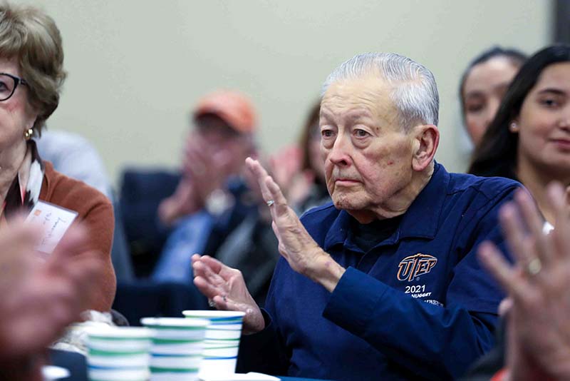 Person seated at a table clapping during the Loya Engineering 2022 Homecoming breakfast.