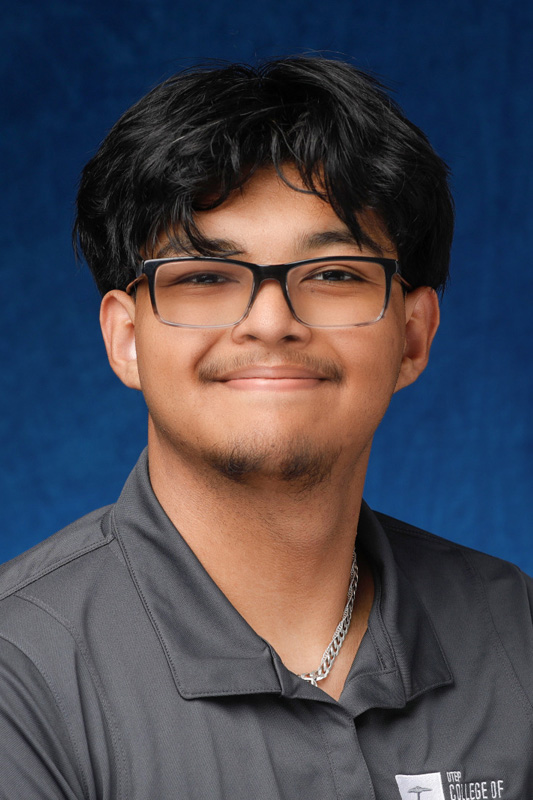Professional headshot of Benjamin Flores wearing glasses and a gray UTEP College of Engineering polo shirt, facing forward against a blue studio background.