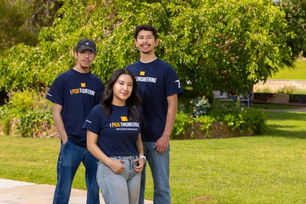 Three Mining Camp student leaders standing outdoors on campus.