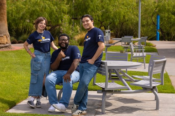 Three Mining Camp student leaders posing near outdoor picnic tables on campus.