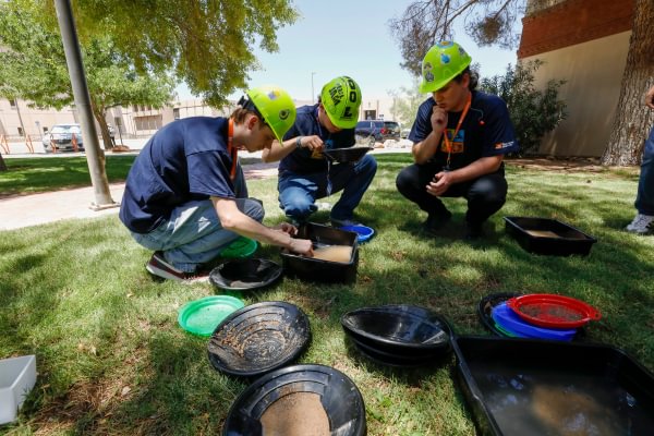Mining Camp participants wearing hard hats during an outdoor hands-on activity.