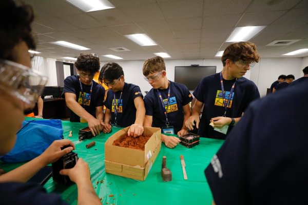 Mining Camp students working together on a hands-on mining activity at a classroom table.