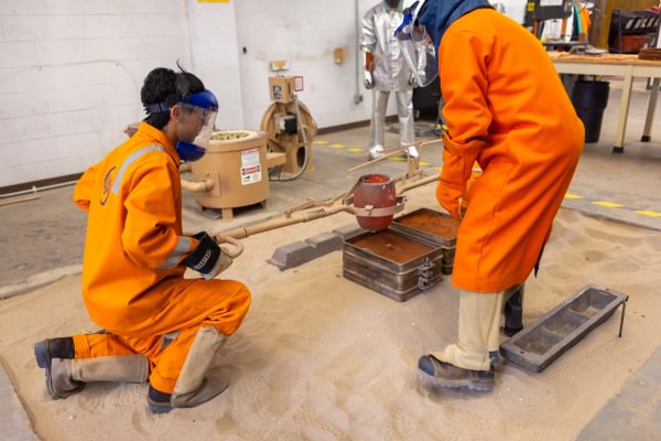 Mining Camp participants in protective clothing working during a foundry activity.