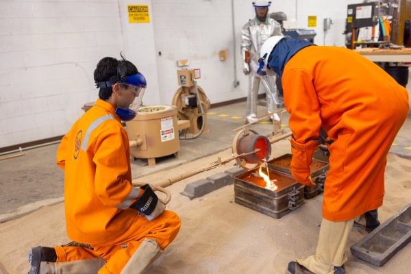 Mining Camp participants handling materials during a foundry casting activity.