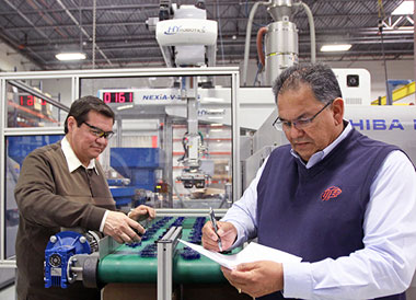 Hector Lopez (right), a field engineer at the Texas Manufacturing Assistance Center, examines Plastic Molding Technology's production line with PMT quality assurance manager Martin Rubio. Photo by Laura Trejo / UTEP News Service