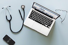 Laptop, stethoscope and phone on a desk