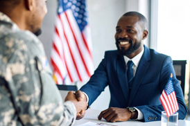 Man in suit shaking the hand of a man in military uniform