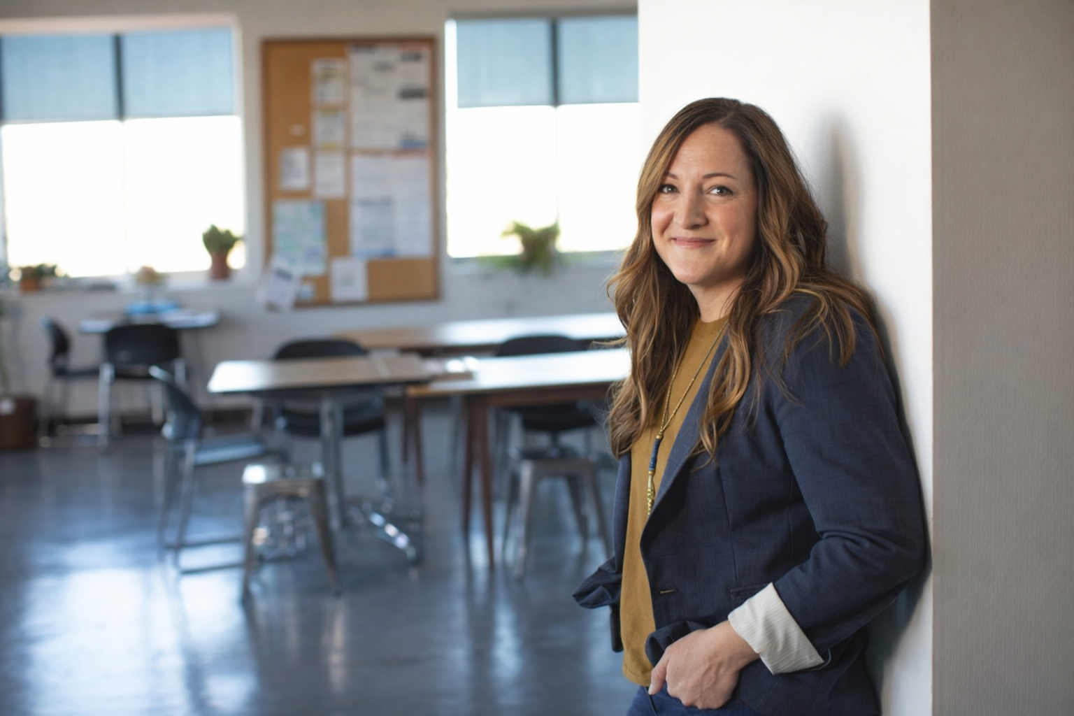Image of female teacher standing against a wall, smiling