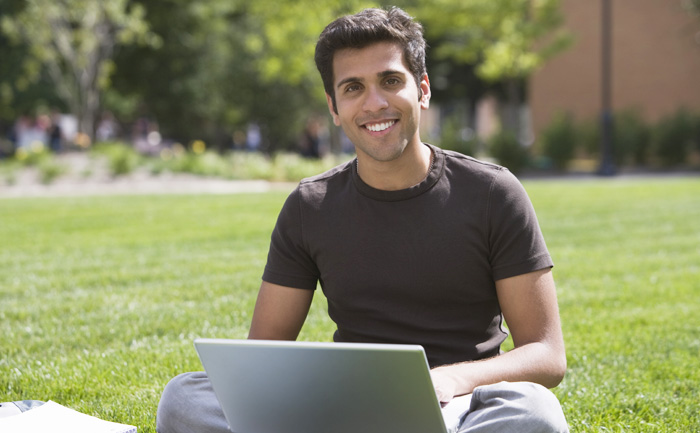 image of young man sitting outside with computer