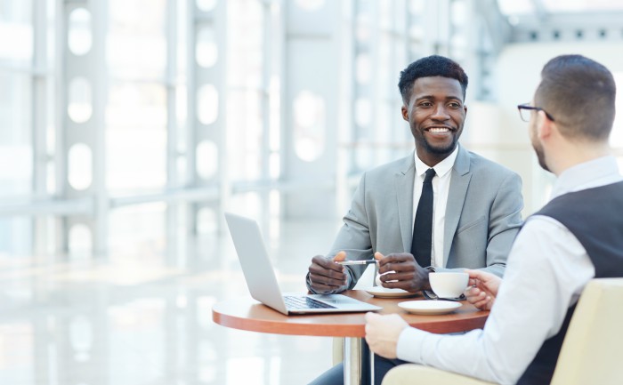 Two business professionals have a conversation over coffee