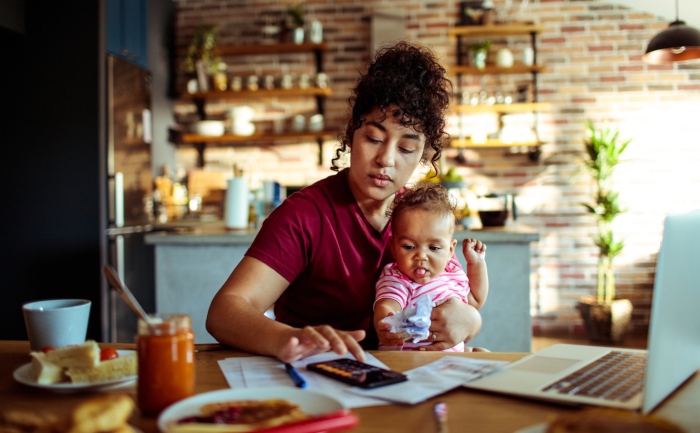 Single mom holding her child while using the calculator on her smartphone | UTEP Connect