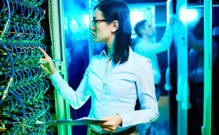 Female systems engineer working on computer network hardware.