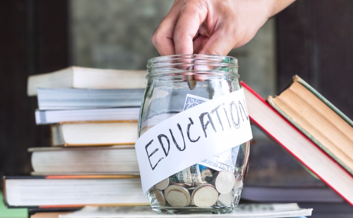 Person putting money in a jar marked for education