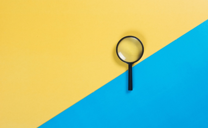 Directly-above shot of a magnifying glass on a blue and yellow surface | UTEP Connect
