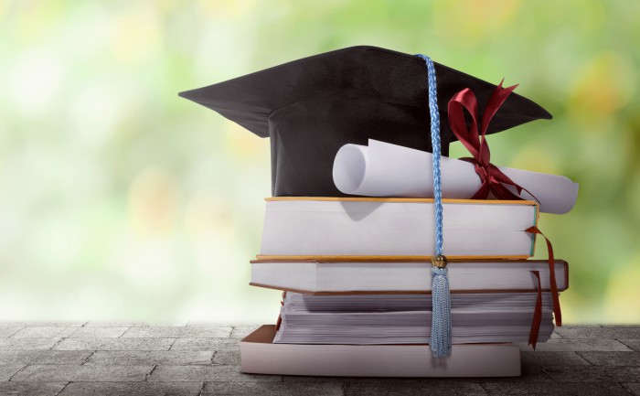 A graduation cap and a diploma on top of a stack of books