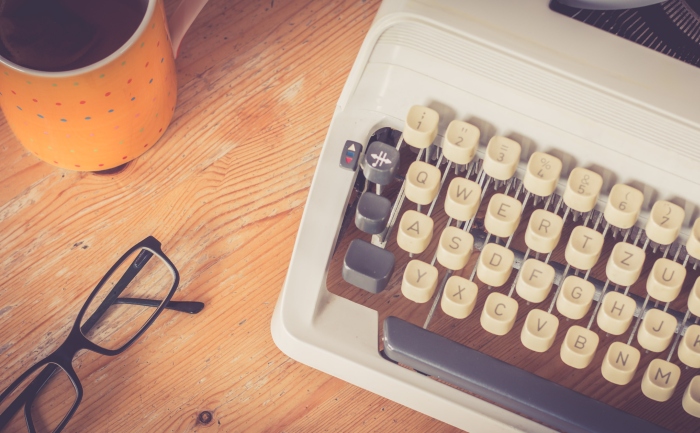 A desk with a coffee mug, glasses, and a typewriter | UTEP Connect | MFA in Creative Writing