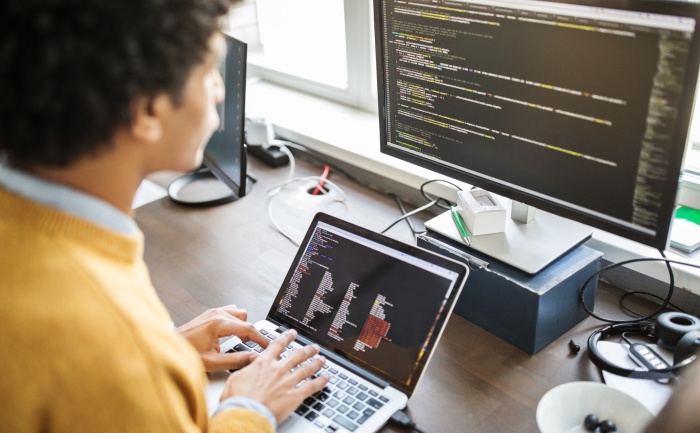 African-American male engineer working on a code on his computer 