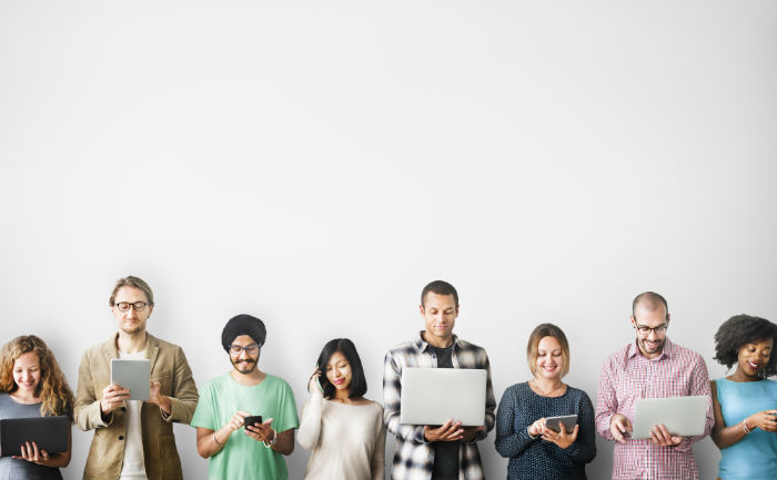 A group of people stand in a line, each holding a tablet or laptop