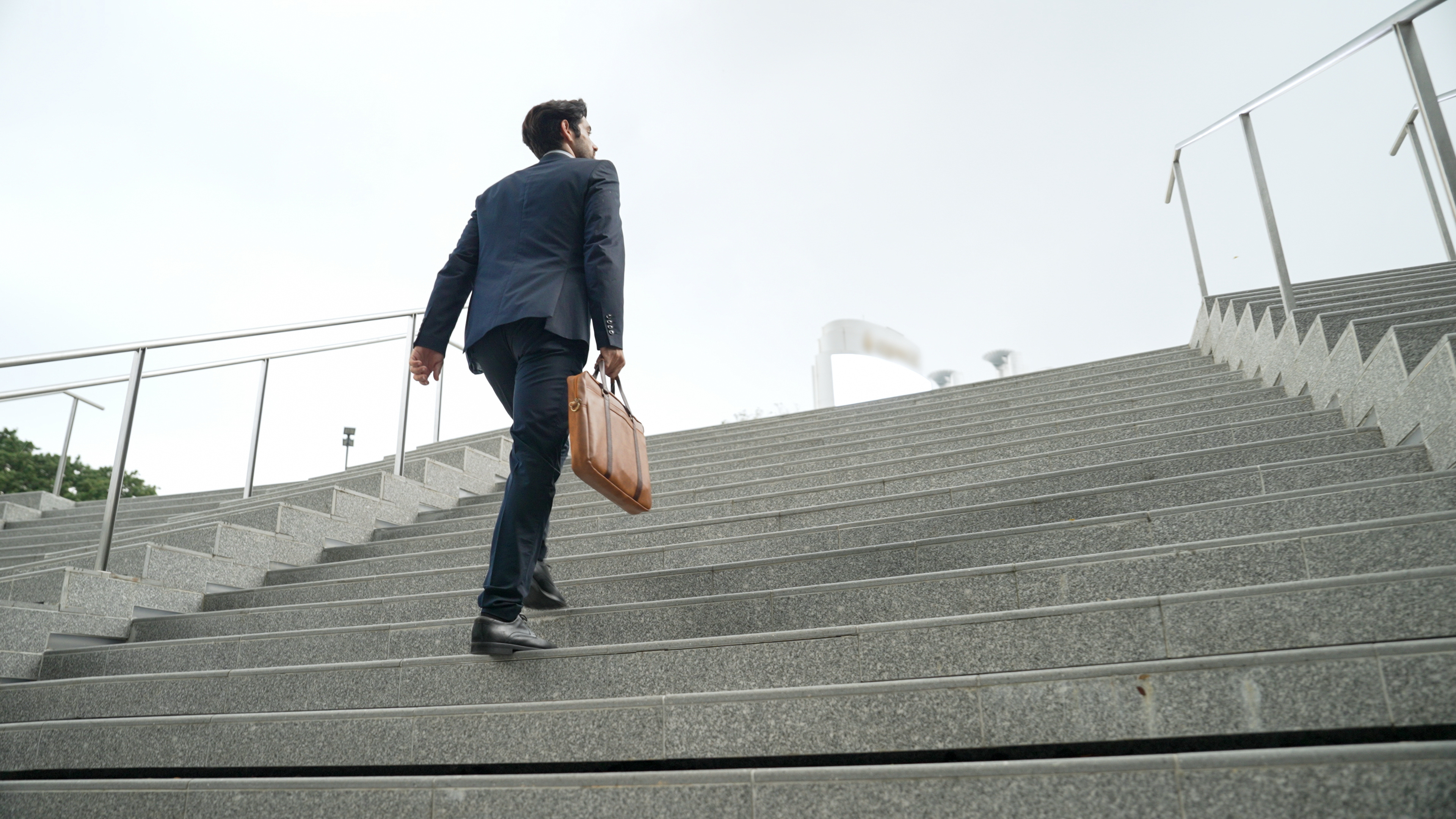 MPA salary expectations 2026; man in suit carrying a briefcase walking up stairs.