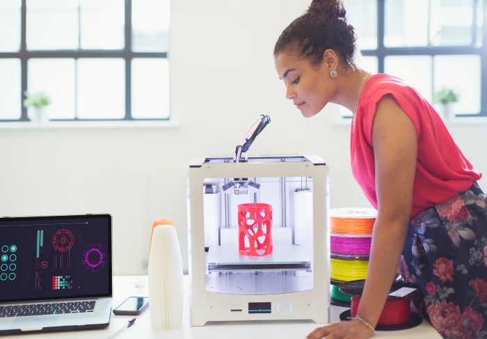 Female designer-entrepreneur monitoring a 3D printer 