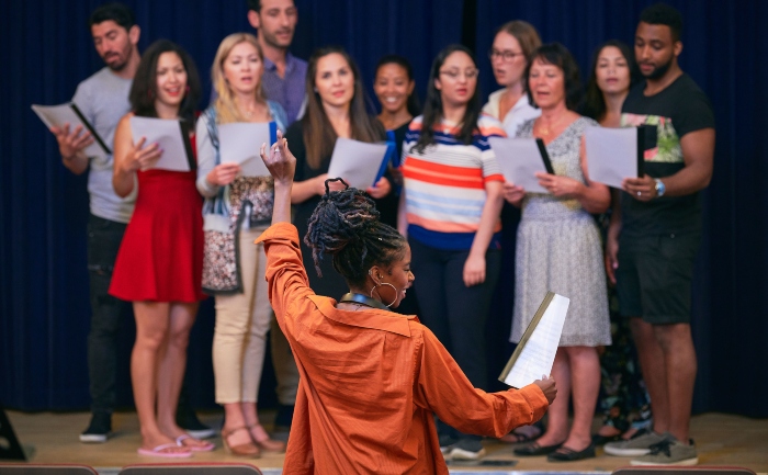 Young female conductor directing choir on stage in auditorium | UTEP Connect