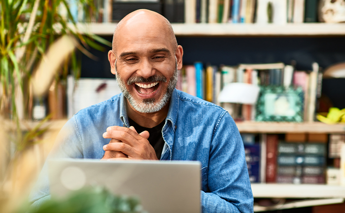 Man (around his 40s) smiles at computer