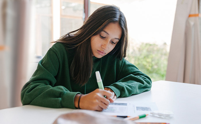 A girl sitting at a desk, highlighting notes.