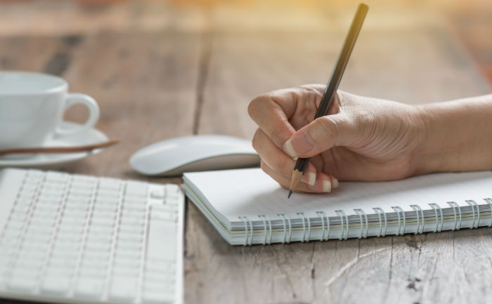 Person writing memory techniques for studying on a notepad.