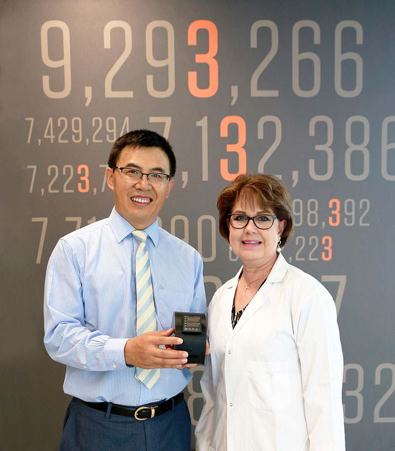UTEP faculty XiuJun James Li, Ph.D., left, and Delfina C. Domínguez, Ph.D., right, were issued a patent for instrument-free biochip technology to detect pneumococcal disease and whooping cough. Photographed in UTEP’s Interdisciplinary Research Building, the background features patent numbers indicating translational development and innovations. Photo: Laura Trejo / UTEP Communications  