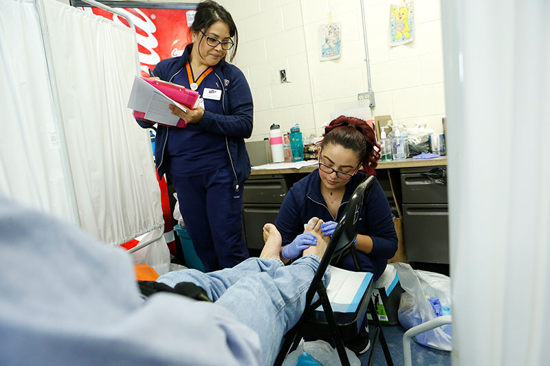Senior nursing majors Claudia Carreron, left, and Jennifer Carrillo conduct a foot exam on a patient during the interdisciplinary H.O.P.E (Health, Opportunity, Prevention, Education) clinic on Oct. 10, 2017, at the Opportunity Center for the Homeless. Photo: J.R. Hernandez/University Communications 