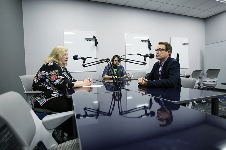 Sue Stanfield, Ph.D., assistant professor of history, left, interviewed Lowry Martin, Ph.D., associate professor of French, for her podcast. In the background is Adrian Meza, an instructional technologist, who produces the show. Photo: J.R. Hernandez / UTEP Communications 